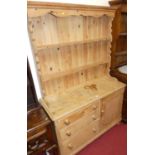 A Victorian pine dresser, the later two-tier open plate rack over base fitted with single cupboard