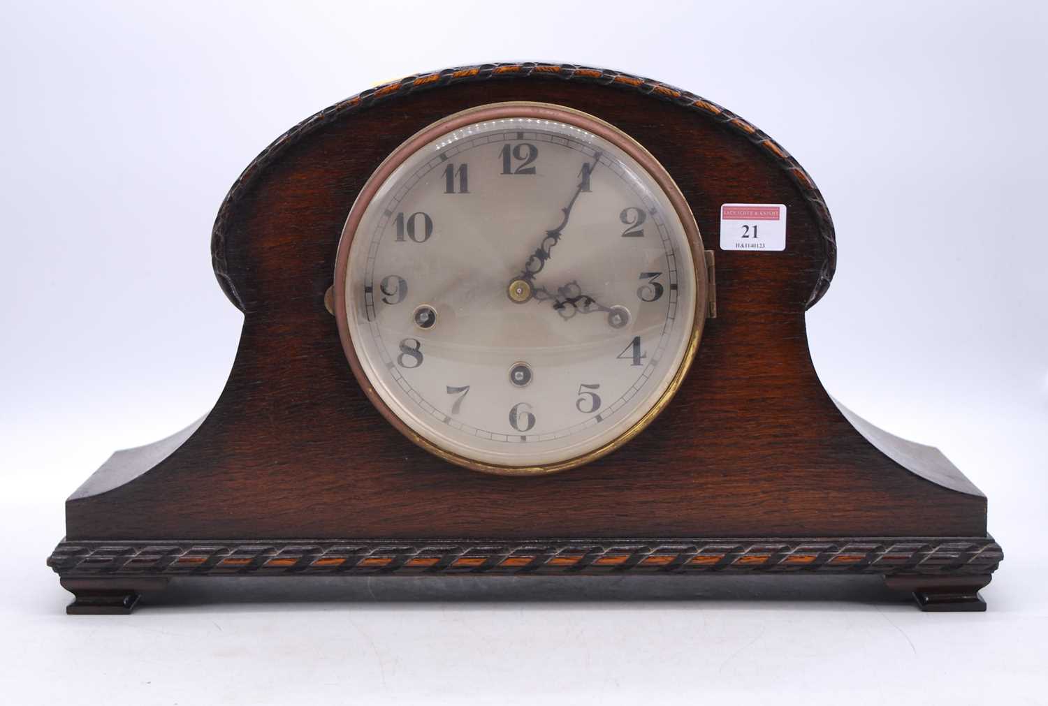 An early 20th century oak cased mantel clock, the silvered dial showing Arabic numerals, the eight-