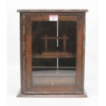 An early 20th century oak smoker's cabinet, the glazed door opening to reveal an arrangement of