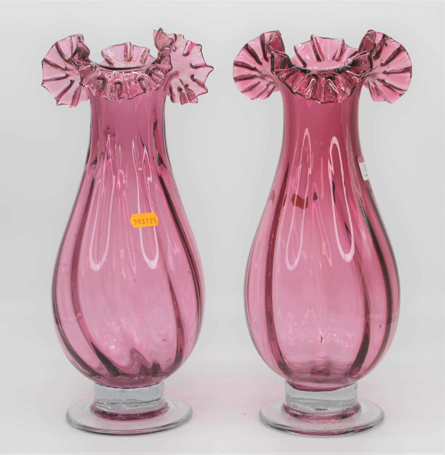 A pair of Victorian style cranberry glass vases, each having a frilled rim, height 37cm