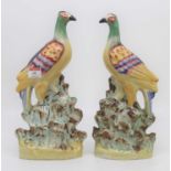 A pair of Staffordshire pottery models of exotic birds, height 32cmThe left is quite crazed with a