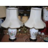 A pair of 20th century floral decorated porcelain table lamps, each having cream shades, height