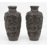 A pair of Chinese carved resin vases, each decorated with a dragon, height 23cm