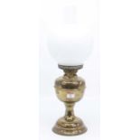 A Victorian brass oil lamp, the milk glass shade above a brass font, height 52cm