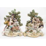 A pair of 19th century hard paste porcelain bocage figure groups, after Chelsea, each depicting a