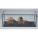 A lacquered brass scale model of a Napoleonic cannon and carriage, mounted on an ebonised plinth