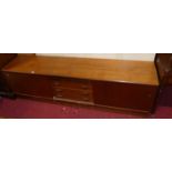 A 1970s teak low sideboard, having four central drawers flanked by sliding doors, w.210cm