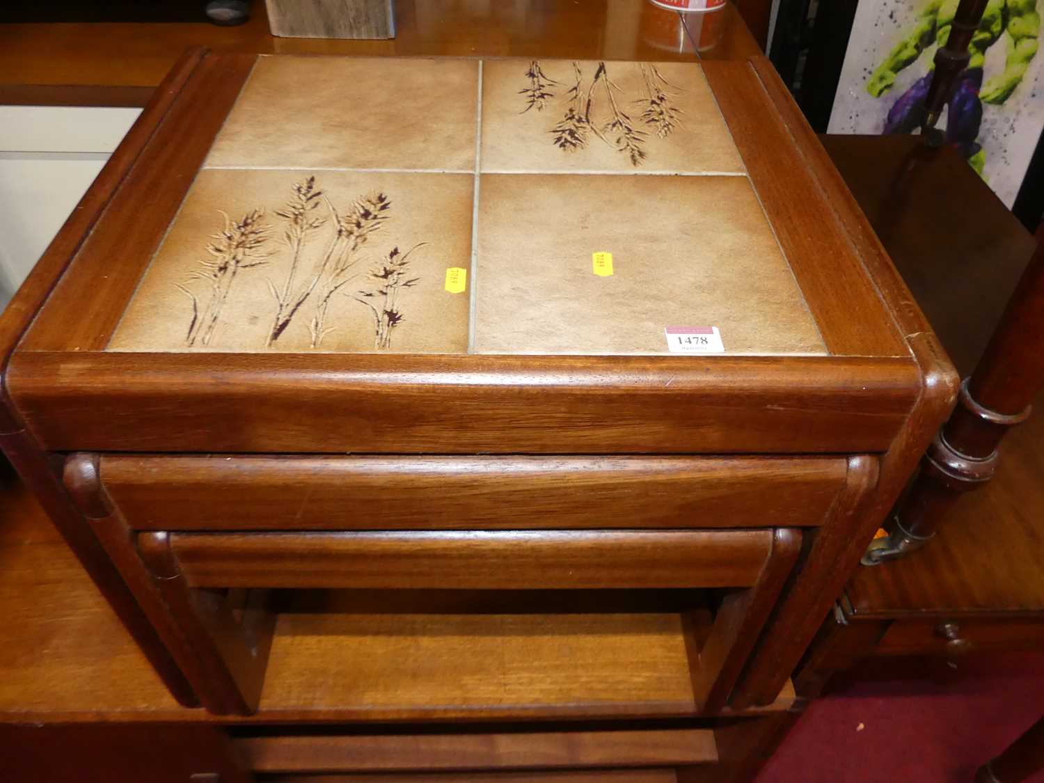 A 1970s teak and tile inset nest of three occasional tables, the largest w.54cm