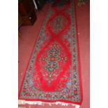 A Persian style red ground woollen Tabriz long hall runner, 395 x 98cm