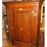 An early 19th century provincial oak and mahogany crossbanded single door hanging corner cupboard
