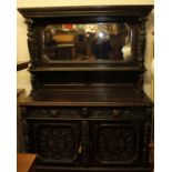 A circa 1900 heavily carved and ebonised oak mirrorback sideboard, having Ionic capped and floral