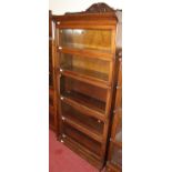 A 1930s oak five-tier stacking bookcase, having raised floral carved ledgeback over typical hinged