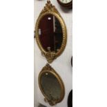 A pair of 19th century giltwood and gesso oval wall mirrors, each with shield and floral scroll