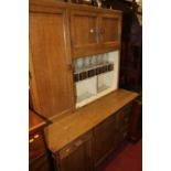 A mid-20th century oak kitchen cabinet, having various drawers, cupboard doors and open compartment,