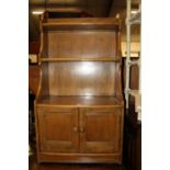 An Ercol mid-elm narrow waterfall bookshelf, having twin lower cupboard doors, w.61cmW: 61cm, H: