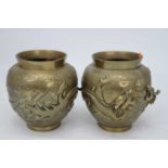 A pair of Chinese brass vases each relief decorated with two dragons chasing a pearl, having