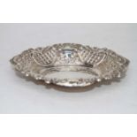 A Victorian style silver bonbon dish of shaped oval form having repoussee floral and C-scrolling