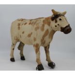 An antique pull-along model of a cow, clad in animal skin, height 38cm