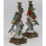 A pair of continental porcelain and gilt metal table candlesticks, each in the form of a parrot