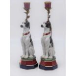 A pair of continental porcelain and gilt metal table candlesticks, each in the form of a seated dog,