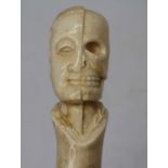 A walking stick, the bone handle carved with the bust of a gentleman half revealing his skull, 93cm