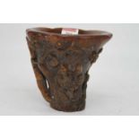 A reproduction simulated rhino horn libation cup, carved with various figures and flowers, and