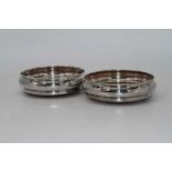 A pair of modern silver bottle coasters, each of squat circular form on turned mahogany bases, dia.