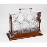 An early 20th century oak three division tantalus, with silver plated mounts containing three cut