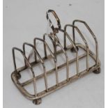 A late Victorian silver toast-rack, having six arched divisions and with loop handle, on octagonal