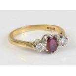 A modern 18ct gold, ruby and diamond three-stone ring, arranged as a centre oval cut ruby flanked to