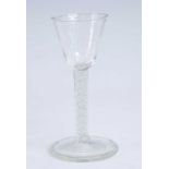 A wine glass, having a round funnel bowl above a multi series air and opaque twist stem and folded