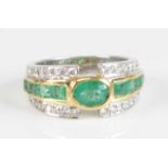A modern white metal, emerald and diamond half hoop ring, arranged as a central oval cut emerald