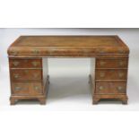 A walnut twin pedestal desk in the 18th century style, the top with feather banding and a gilt