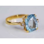 A yellow metal aquamarine set dress ring, the four-claw set oval cut aquamarine measuring approx