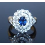 A yellow and white metal, sapphire and diamond oval cluster ring, featuring a centre oval sapphire