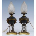 A pair of circa 1900 bronzed metal and gilt brass lamps, each having frosted glass flaming torch