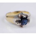 A yellow and white metal sapphire set heavy single stone ring, comprising a round faceted sapphire