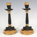 A pair of circa 1900 French bronze and gilt bronze candlesticks, each on lion paw triform bases