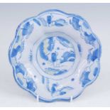 A Delft blue and white dish, late 17th century, of lobed form, the well decorated with an eastern