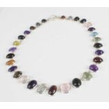 A white metal multi-stone necklace, featuring graduated oval cabochons of garnet, tourmalinated