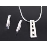 A white metal diamond pendant and earring set, the pendant comprising a tapered bar with three