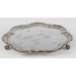 An Edwardian silver salver, of shaped circular form with a piecrust border, standing upon three