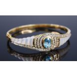 A yellow metal blue topaz, diamond and mother of pearl hinged oval bangle, featuring a centre oval