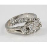 A white metal diamond crossover ring, having three graduated round brilliant cut diamonds in the