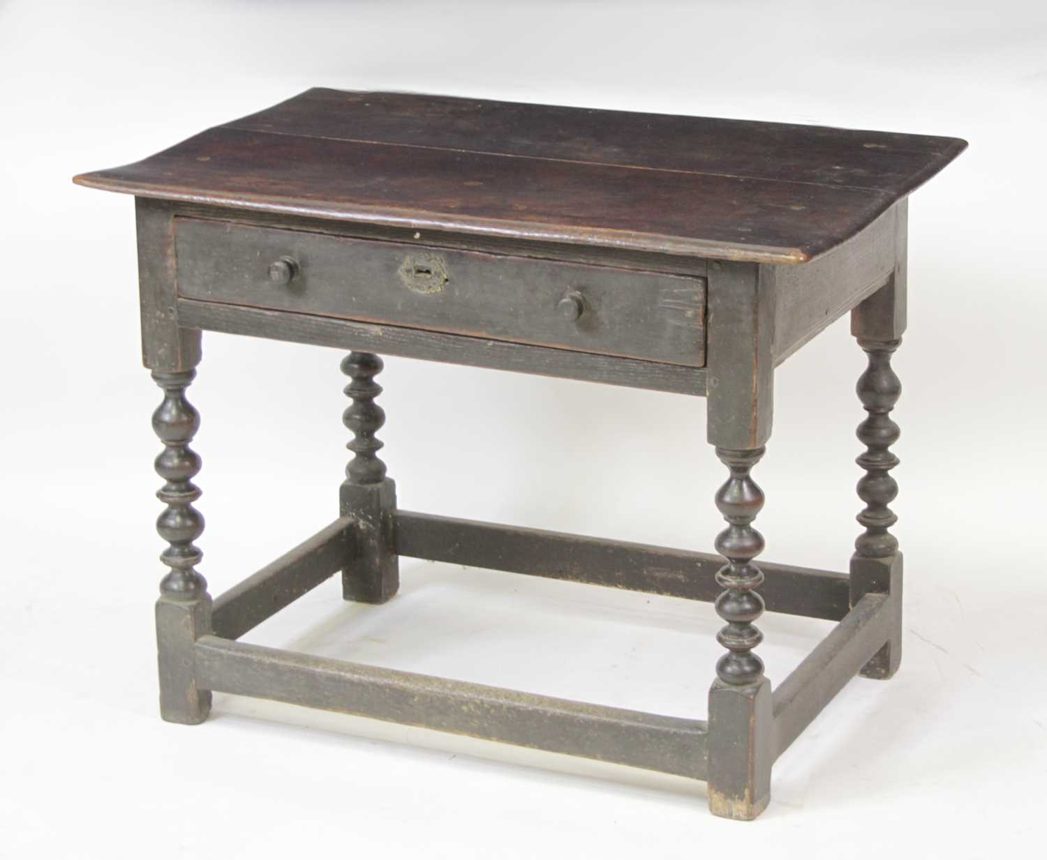 A circa 1700 joined oak single drawer side table, having a two-plank top and raised on bobbin turned