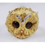 A yellow metal three-dimensional owl head ring, featuring an owl's face in textured finish, with