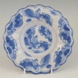 A Delft blue and white lobed dish, late 17th century, decorated with figures within a landscape,