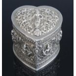 A circa 1900 Indian white metal box and cover, of heart shape, decorated with deities and exotic