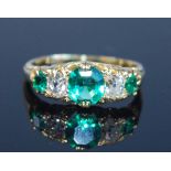 A yellow metal, emerald and diamond five stone half hoop ring, comprising three graduated oval