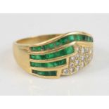 A modern emerald and diamond half-hoop ring, arranged as four rows of 29 trap-cut channel set